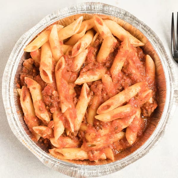 Penne pasta with meat sauce in a foil takeout container, with a fork visible.